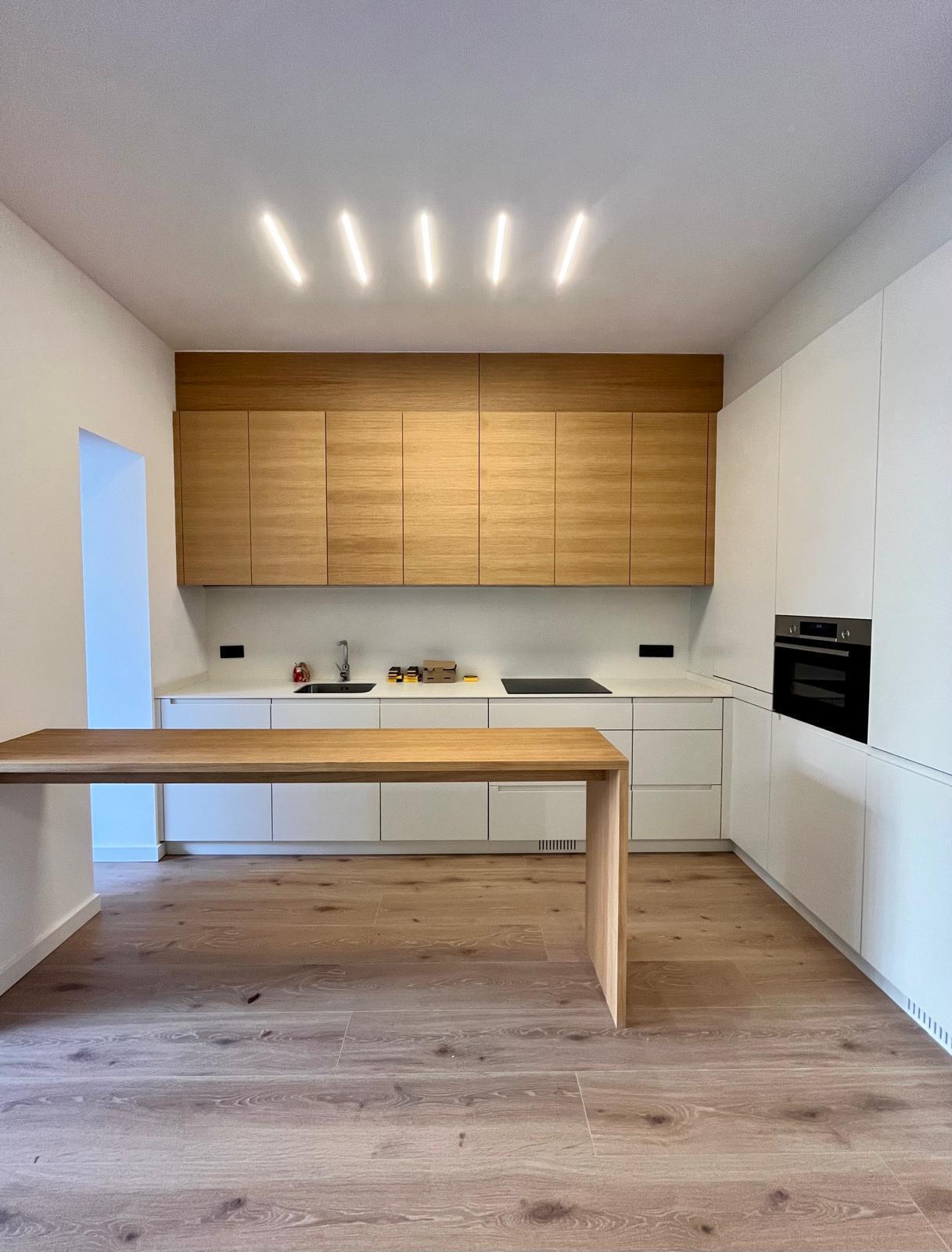Cocina de frente, con los armarios de roble y la encimera blanca