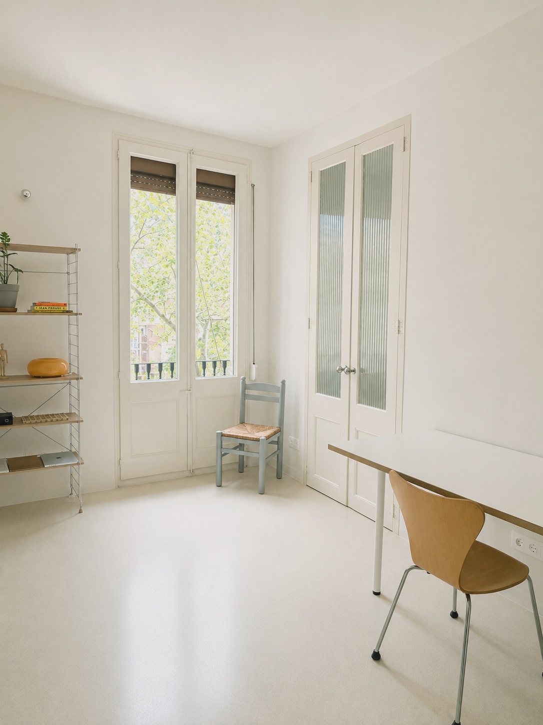 Comedor junto al balcón, con mesa blanca y silla de madera bajo la ventana