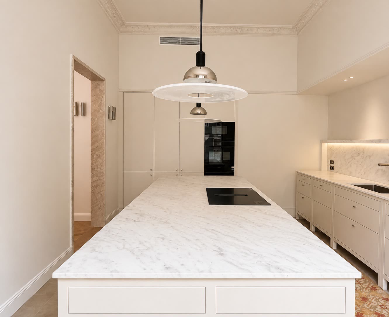 Cocina con isla de mármol de Carrara, horno de columna y frente de mármol retroiluminado